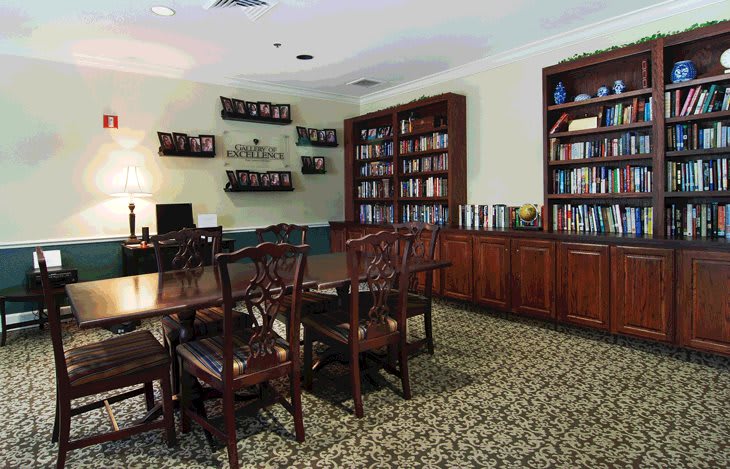 A cozy library room with wooden furniture and bookshelves lining the walls.