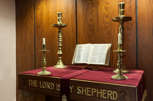 An altar adorned with candles and an open Bible, highlighting a serene atmosphere for worship.