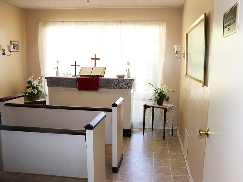 A small chapel interior featuring an altar with crosses and pews.