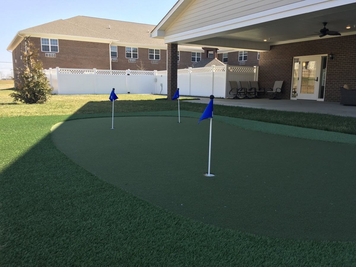 A backyard putting green with blue flags and artificial turf.