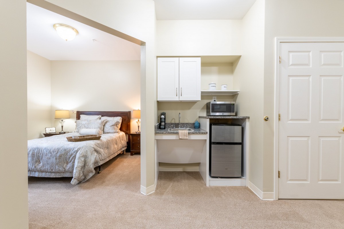 A cozy apartment with a bedroom and a small kitchenette area.