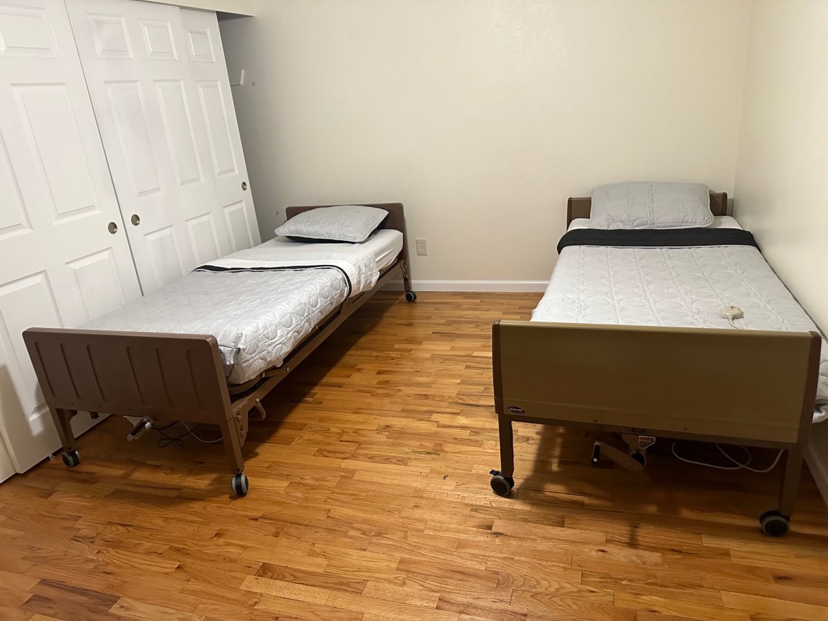 A minimalist bedroom featuring two twin beds on a wooden floor.