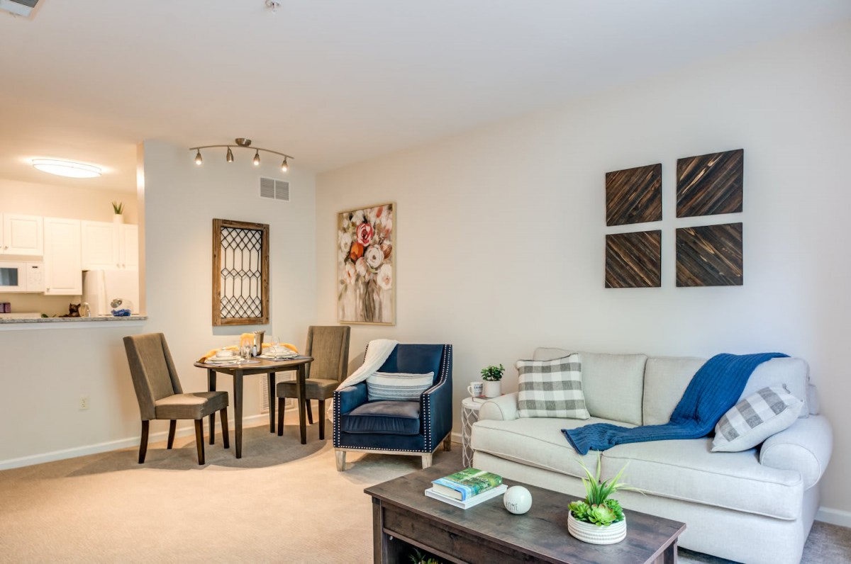 A modern living room with a sofa, dining table, and artwork on the walls.