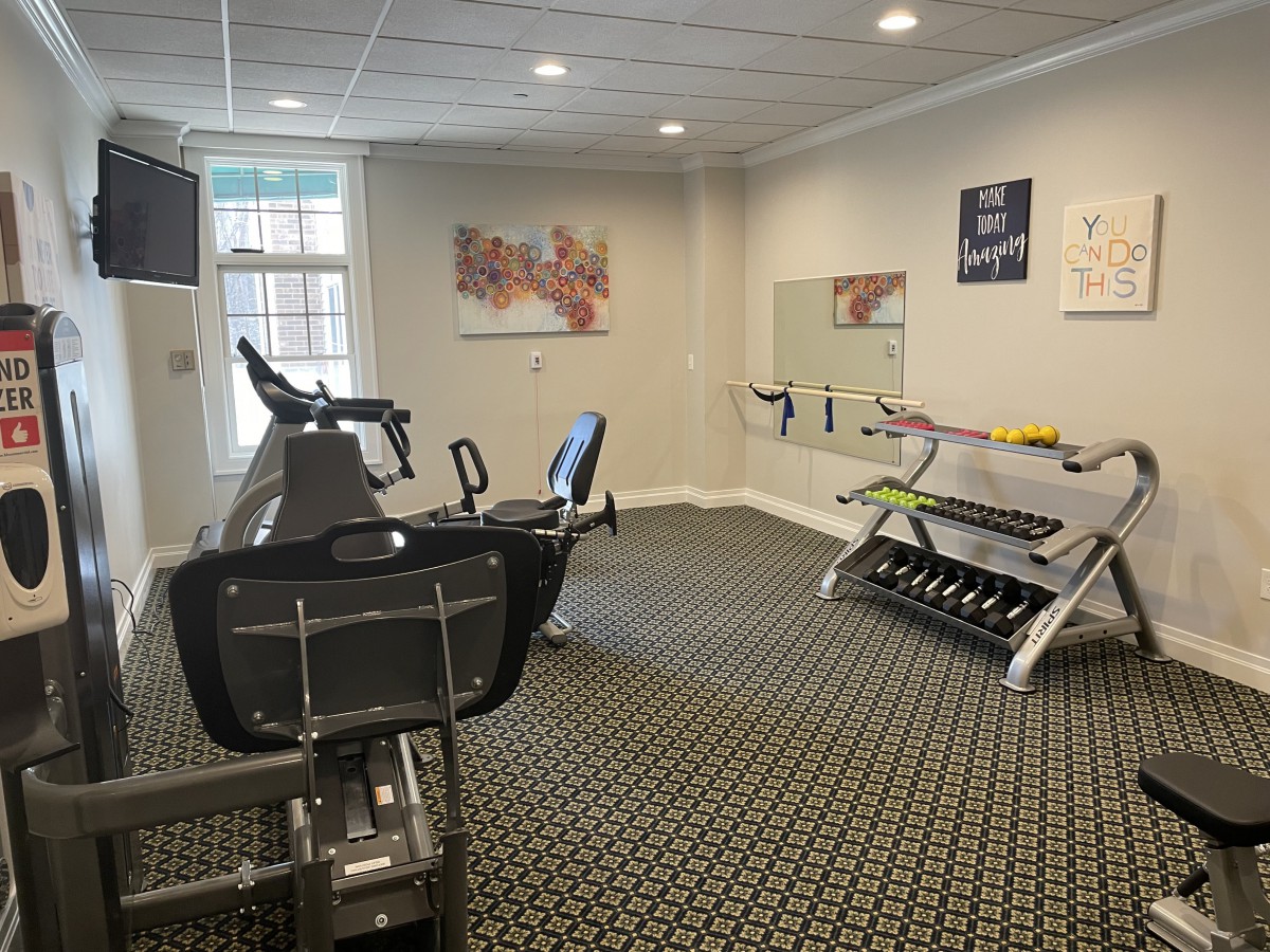 A small gym setup with exercise equipment including a treadmill and a dumbbell rack.