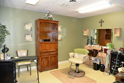 A cozy beauty salon featuring a comfortable barber chair, wooden shelves, and soft green walls.