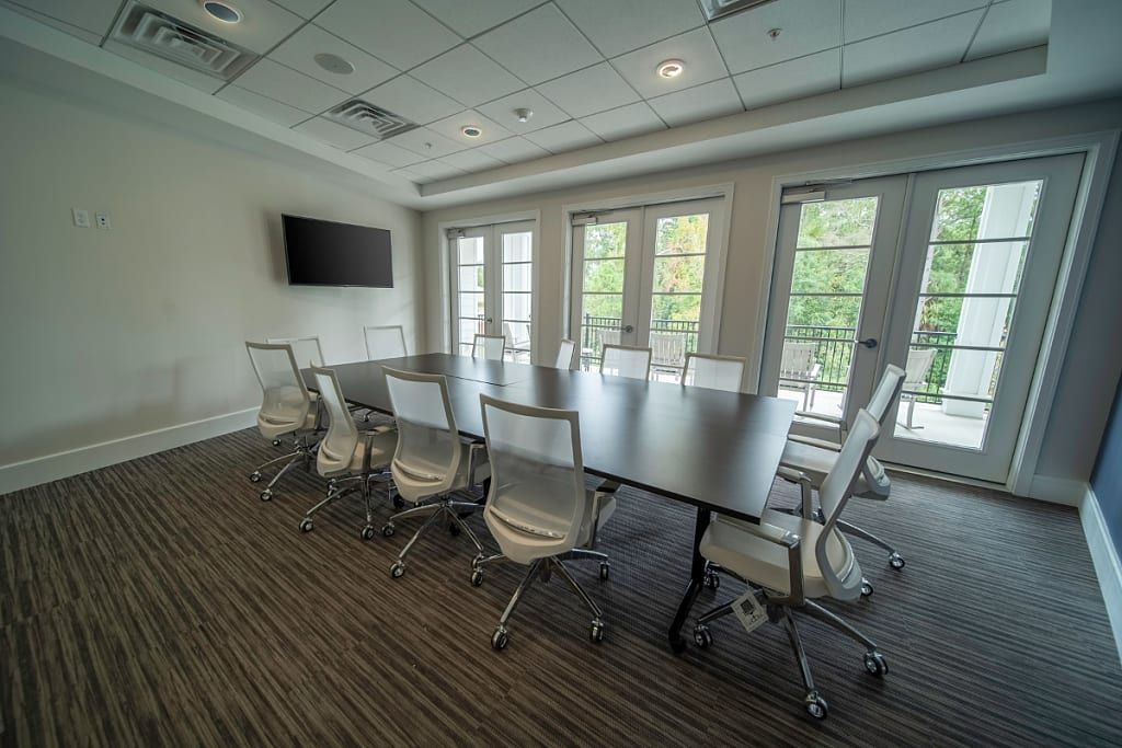 A modern conference room with a large table, chairs, and a television.