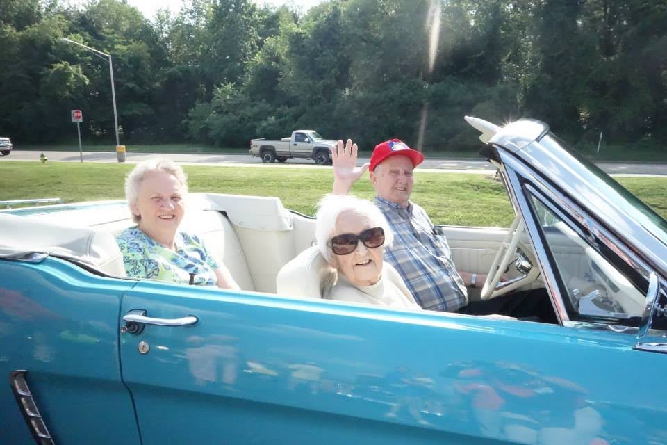 Three people enjoying a ride in a classic convertible on a sunny day.