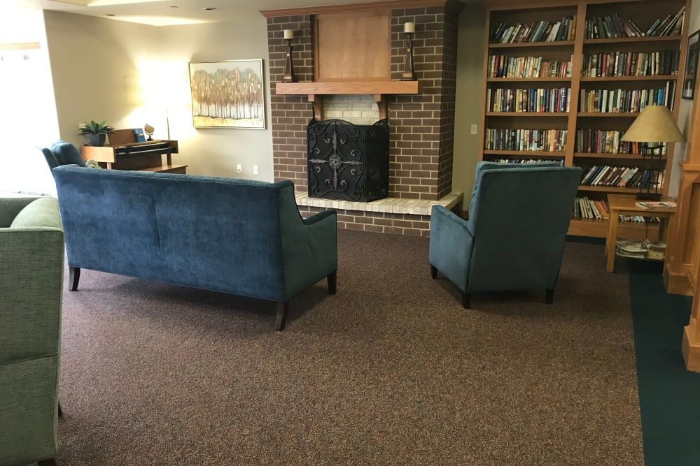 A cozy living room with blue sofas facing a fireplace and surrounded by bookshelves.