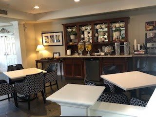A cozy dining area with tables, chairs, and a beverage station.