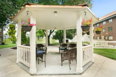 A cozy garden gazebo with outdoor seating and hanging plants.