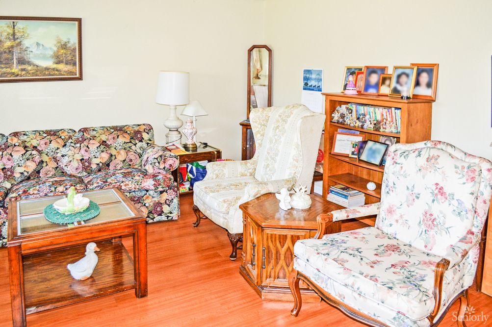 A cozy living room with floral-patterned furniture and various decorations.