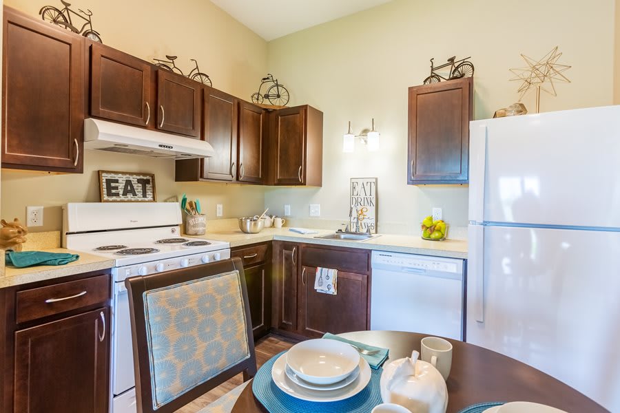 A cozy kitchen with dark wooden cabinets, a dining table set, and various appliances.