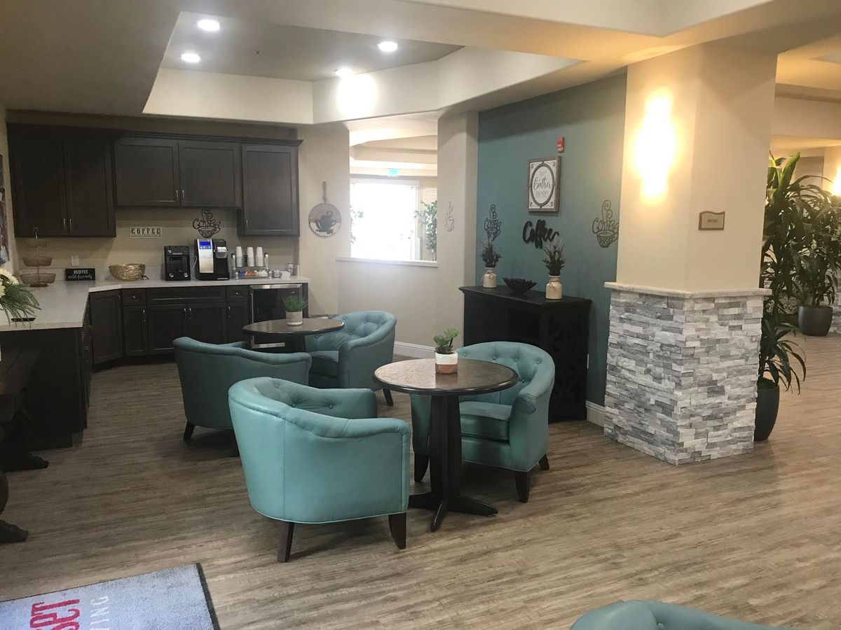 A cozy lounge area featuring modern decor with teal chairs and round tables.