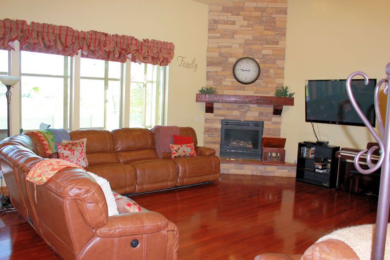 A cozy living room featuring leather couches, a brick fireplace, and a television.