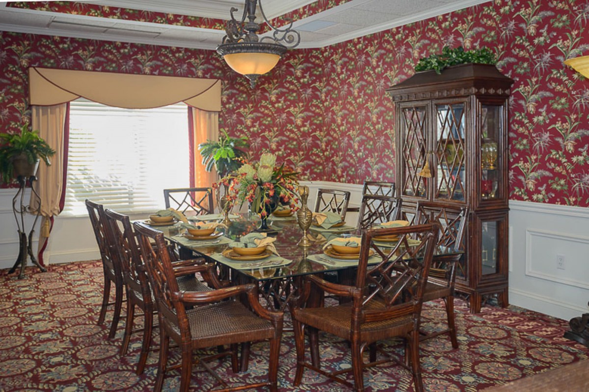 A traditional dining room with a formal table setting and elegant decor.