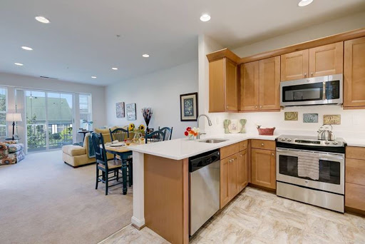 A modern kitchen featuring wooden cabinets and stainless steel appliances, seamlessly connected to a cozy dining area.
