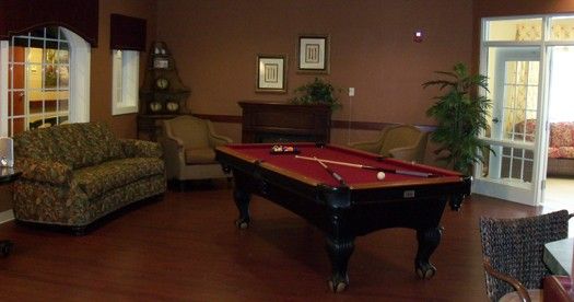 A cozy game room featuring a pool table with red felt and comfortable seating.