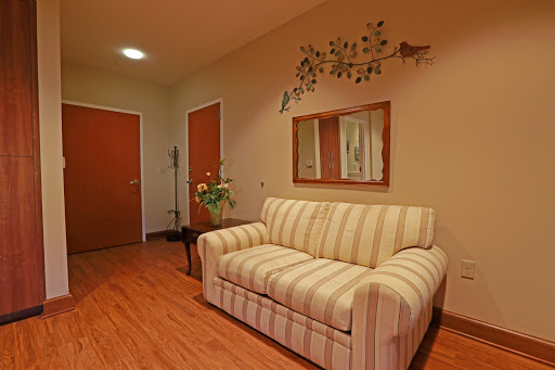A cozy living room featuring a striped sofa, decorative wall art, and wooden floors.