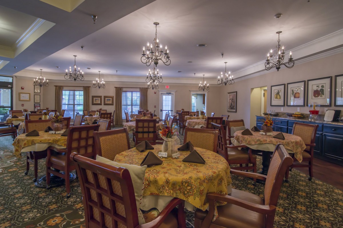 An elegant dining room with multiple tables and chandeliers, showcasing a well-decorated interior.