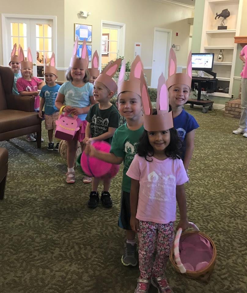 Children wearing bunny ears and holding baskets, lined up for an Easter activity.