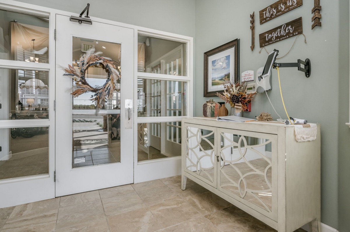 A well-decorated entryway featuring a mirror-front cabinet, wall art, and a wreath on glass doors.