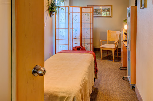 A serene massage room designed for relaxation and wellness, featuring a massage table and calming decor.