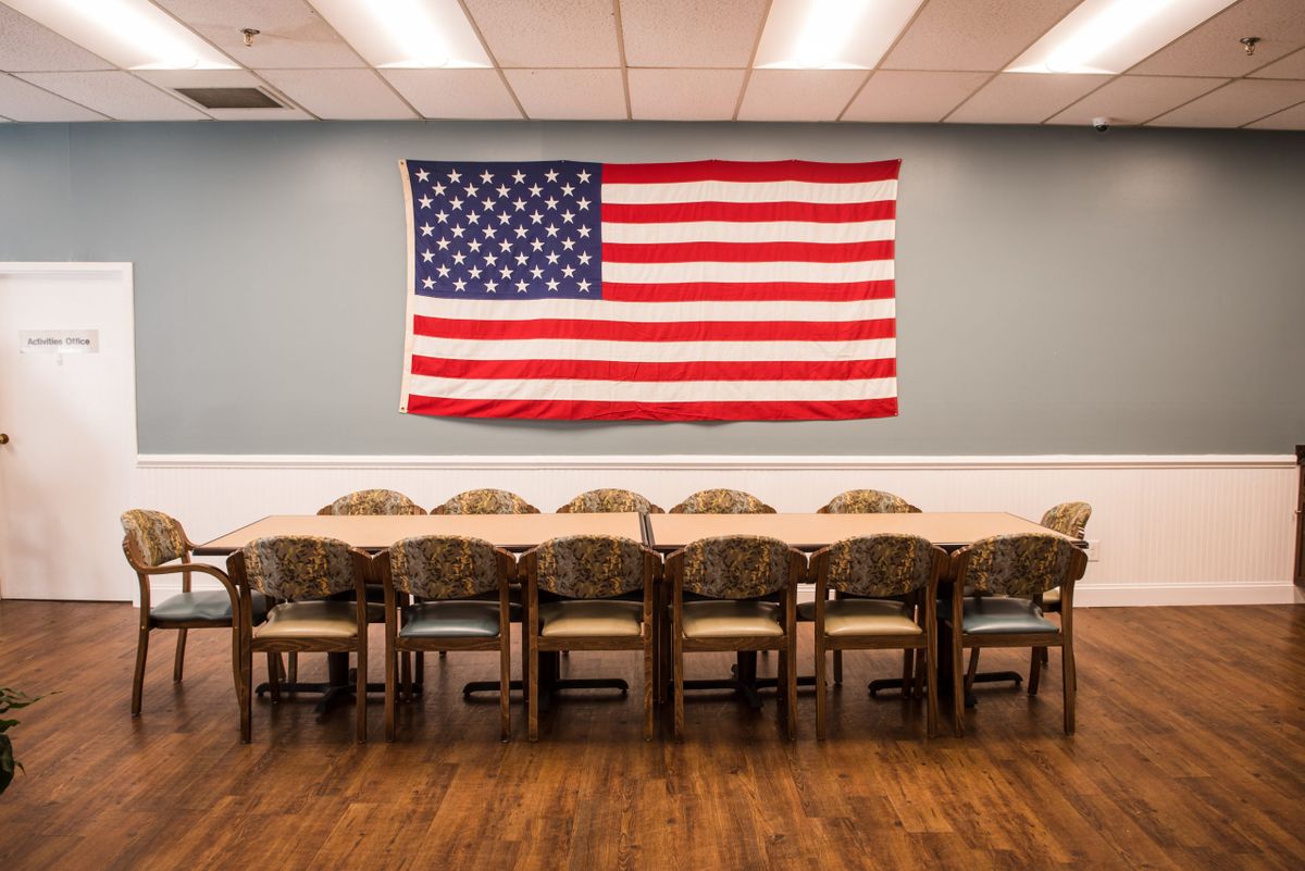 A conference room with an American flag displayed on the wall above a meeting table and chairs.