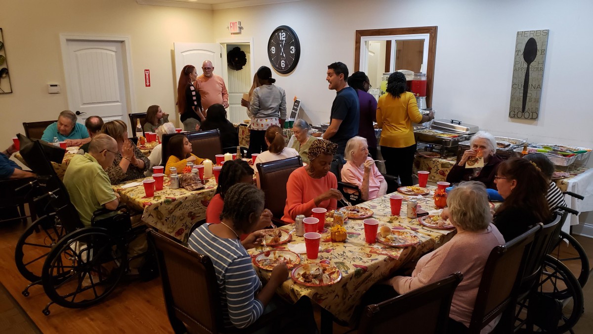 A community gathering for a meal, with people sitting at tables and socializing.