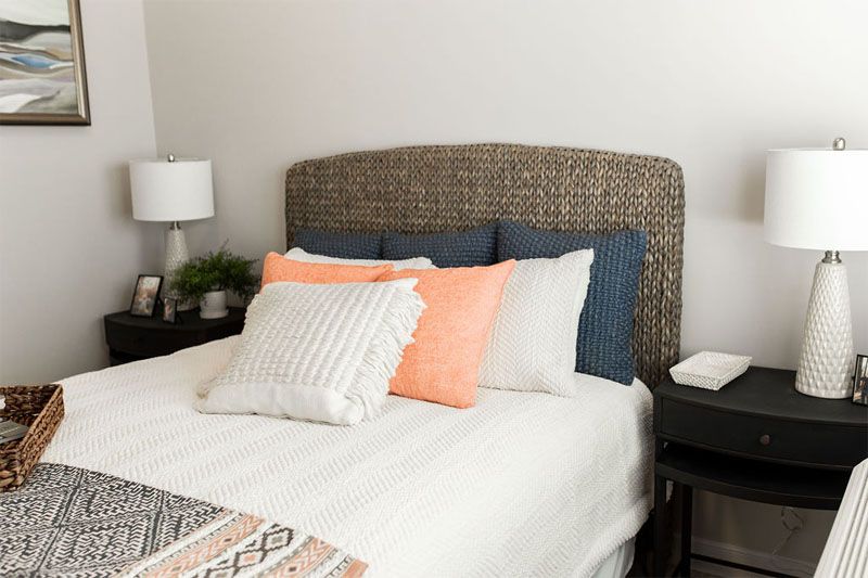 A cozy bedroom with a neatly made bed, featuring colorful pillows and a stylish headboard.
