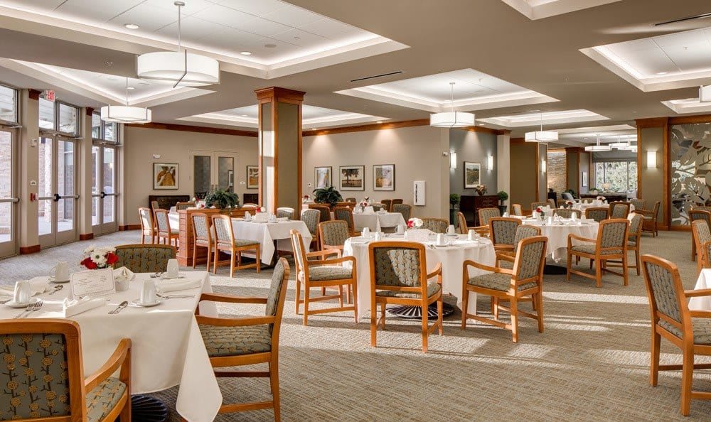 An elegant restaurant dining room with neatly arranged tables and chairs, featuring warm lighting and tasteful decor.