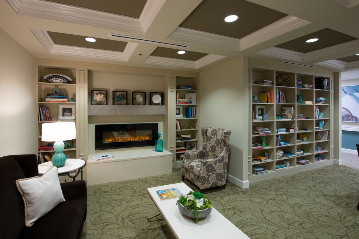 A cozy library room with a fireplace and bookshelves.