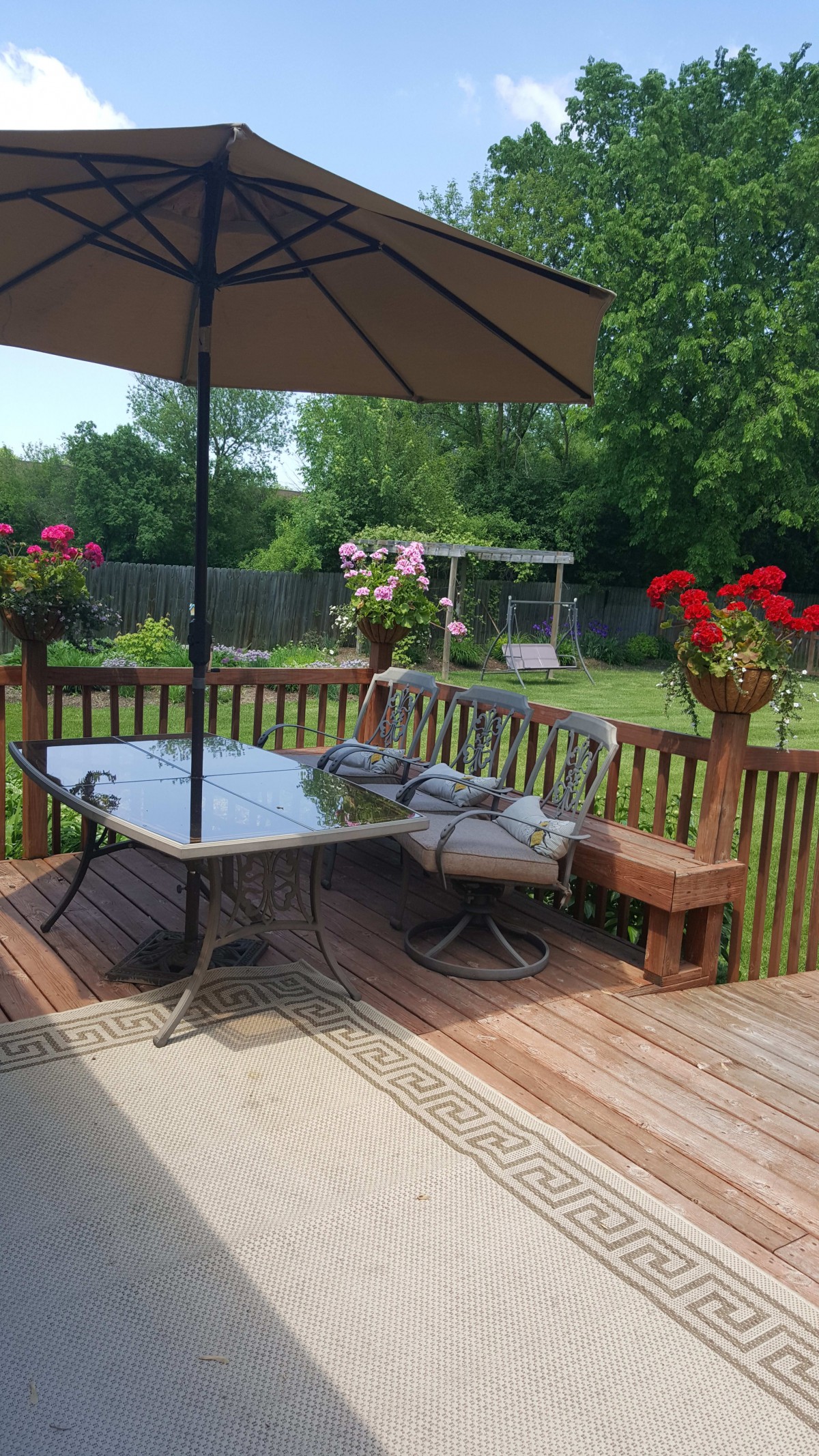 A cozy patio setup with a table, chairs, and an umbrella, surrounded by vibrant flowers.
