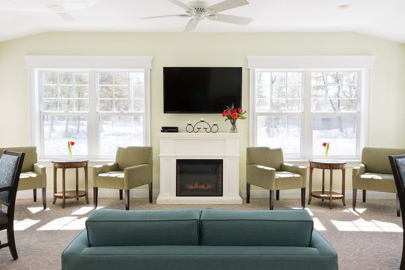 A modern living room with a fireplace and TV, featuring comfortable seating and abundant natural light.
