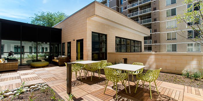 A modern outdoor patio area with tables and chairs, adjacent to a contemporary building.