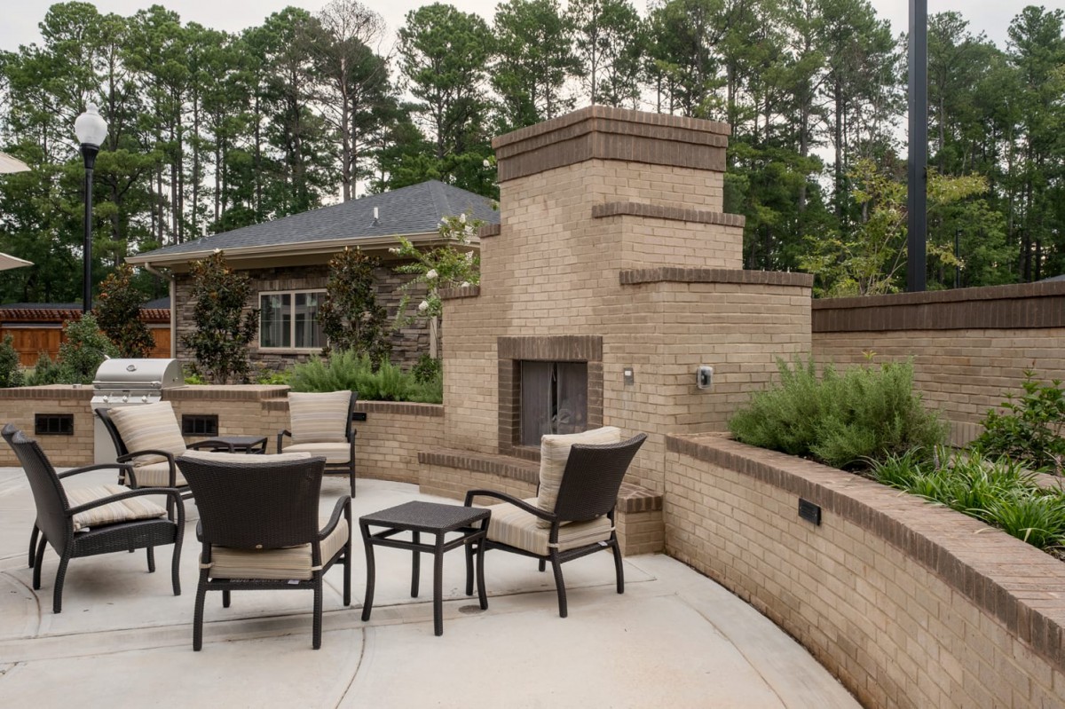 A spacious outdoor patio with a brick fireplace surrounded by comfortable seating.