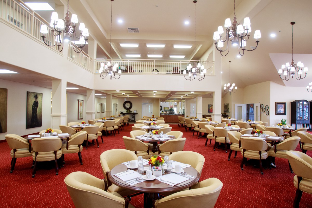 Spacious and elegant dining hall with arranged tables and chandeliers.