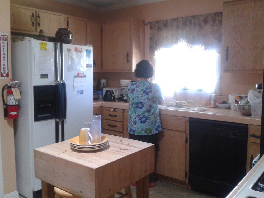 A person standing in a kitchen, facing the sink.