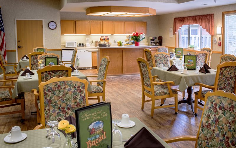 A warmly decorated dining area with tables and chairs, adjacent to a kitchen counter.
