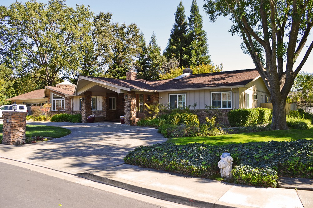 A suburban house with a well-maintained front yard and driveway, surrounded by trees.