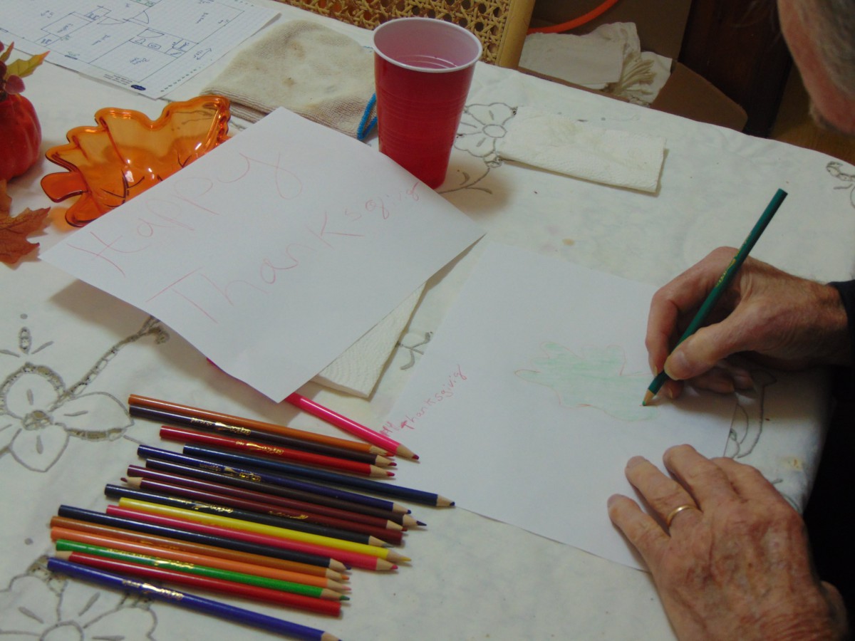 A person sketching on a sheet of paper with colored pencils scattered around.