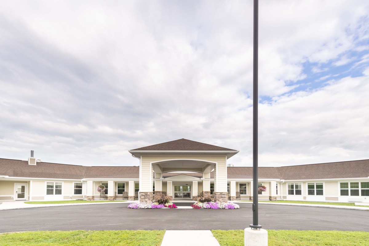 A wide-angle view of a building entrance with a cloudy sky backdrop.