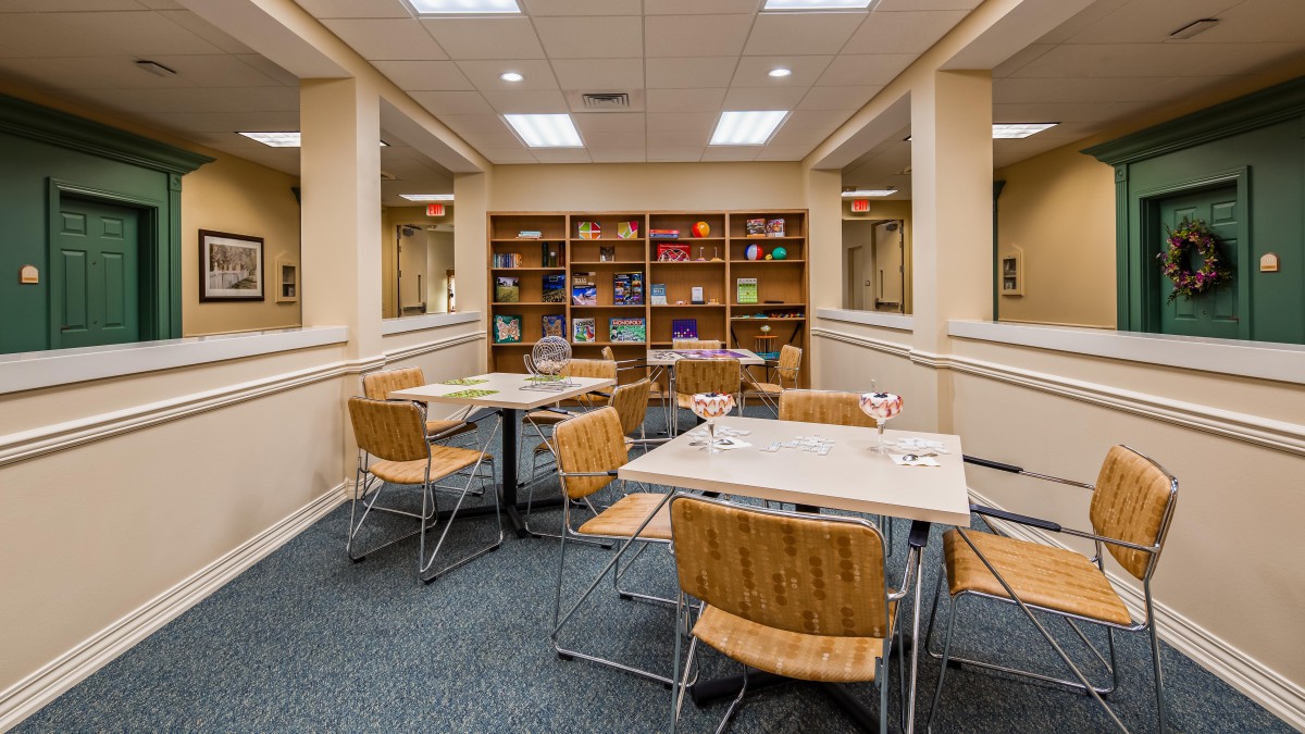 A cozy library reading room with tables and chairs surrounded by bookshelves.