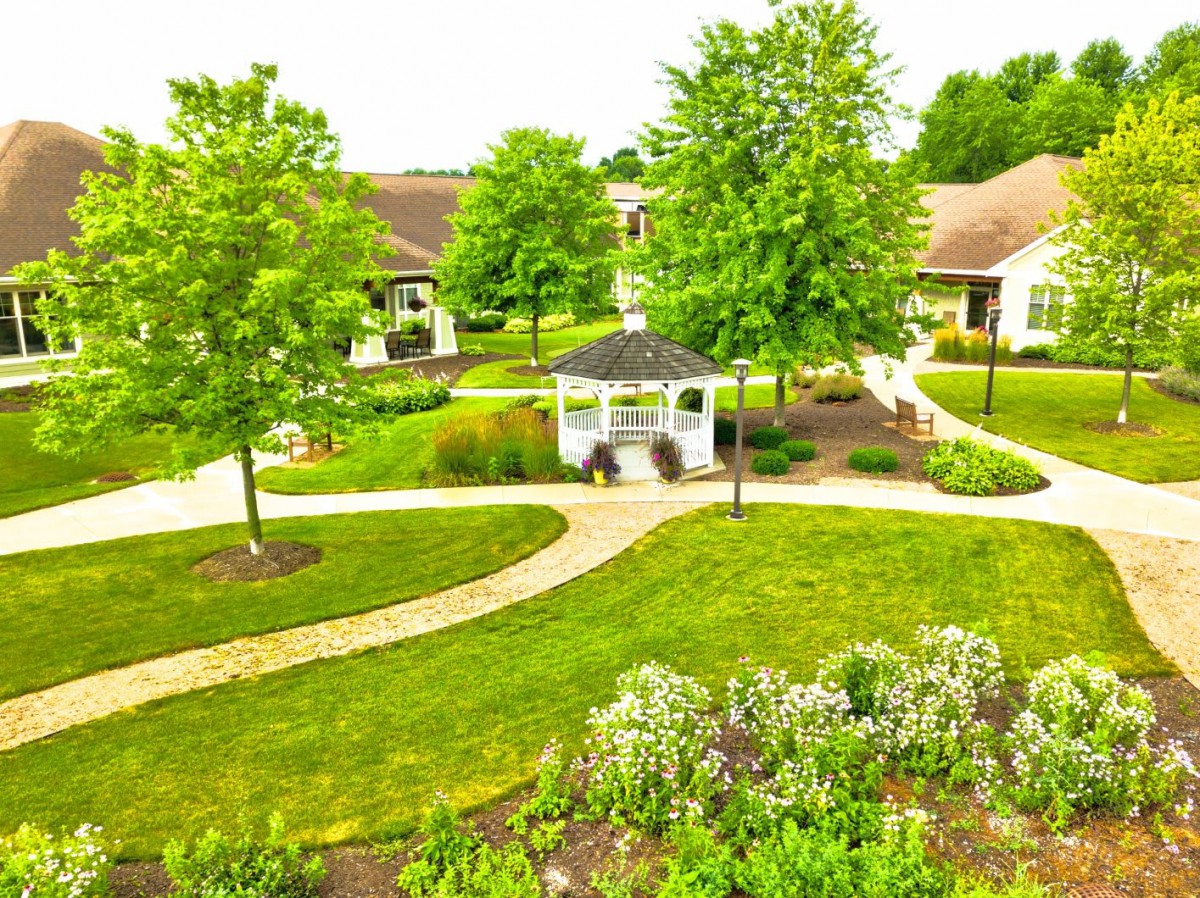 A peaceful garden with a gazebo and pathways surrounded by lush greenery.