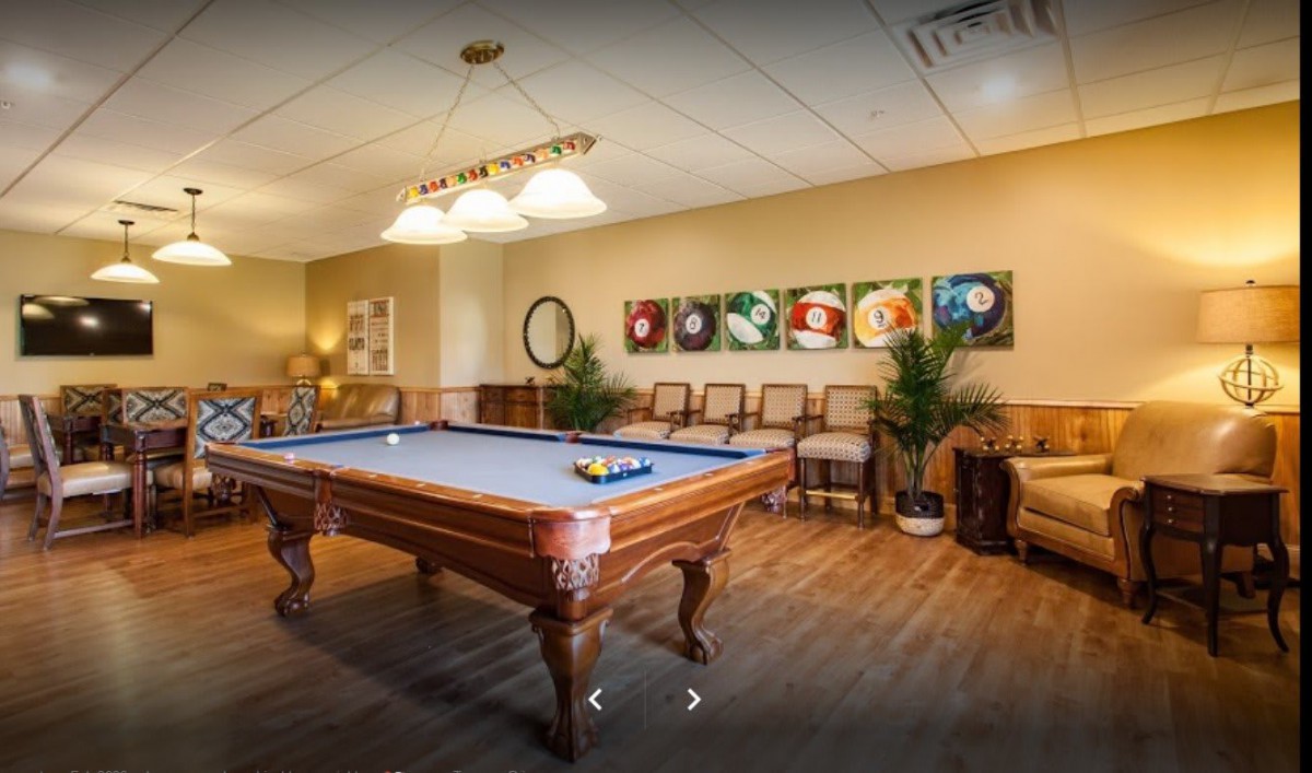 A cozy game room featuring a billiards table with stylish lighting and artistic decor.
