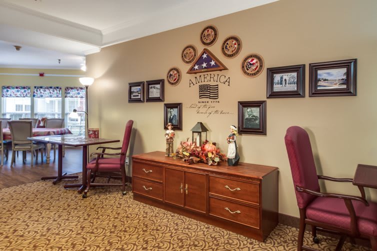 A warmly decorated hallway featuring a wooden sideboard, patriotic wall art, and fall-themed decorations.