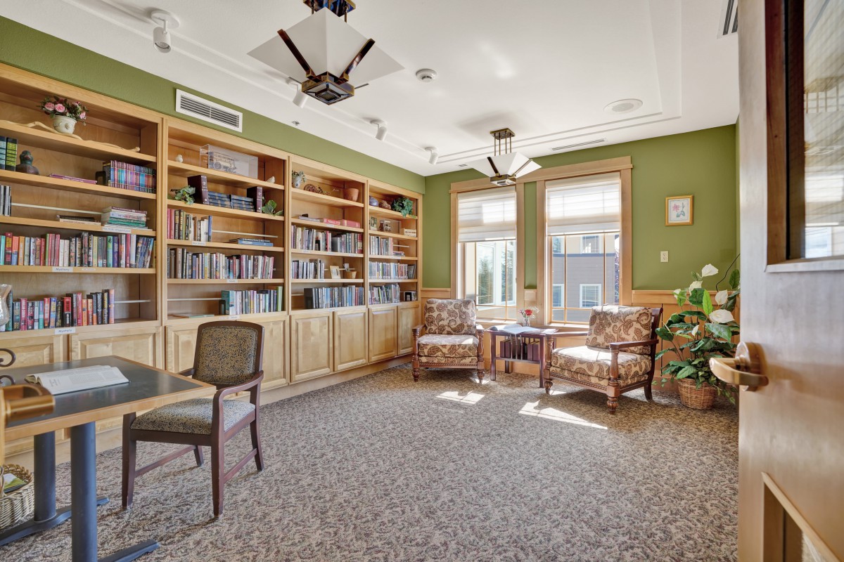 A cozy library reading room with bookshelves, comfortable chairs, and natural light streaming through the windows.