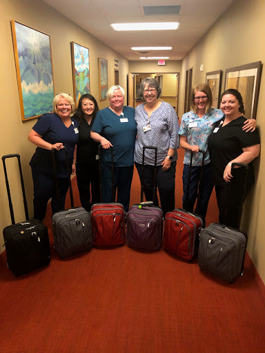 A cheerful group of hospital staff posing with their luggage in a hallway.