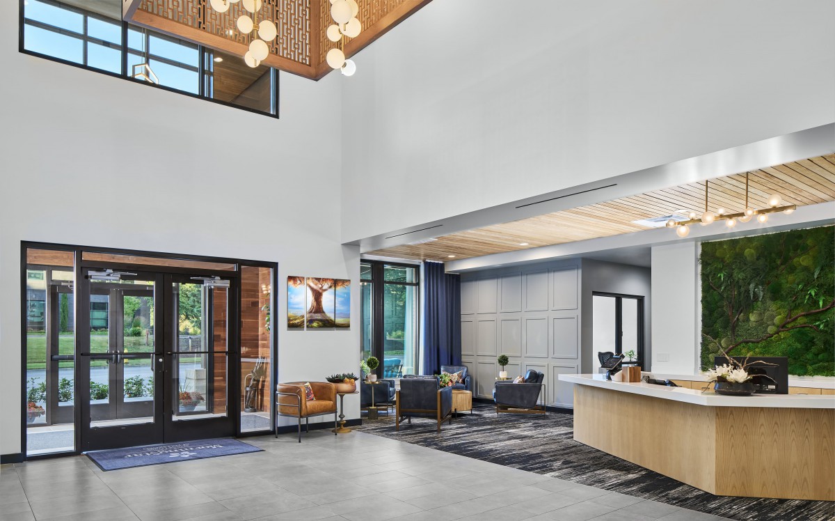 A modern lobby with a reception desk and comfortable seating area, featuring contemporary decor and ample natural light.