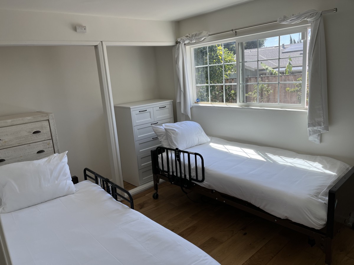 A bright, minimalist bedroom with two beds and ample natural light.