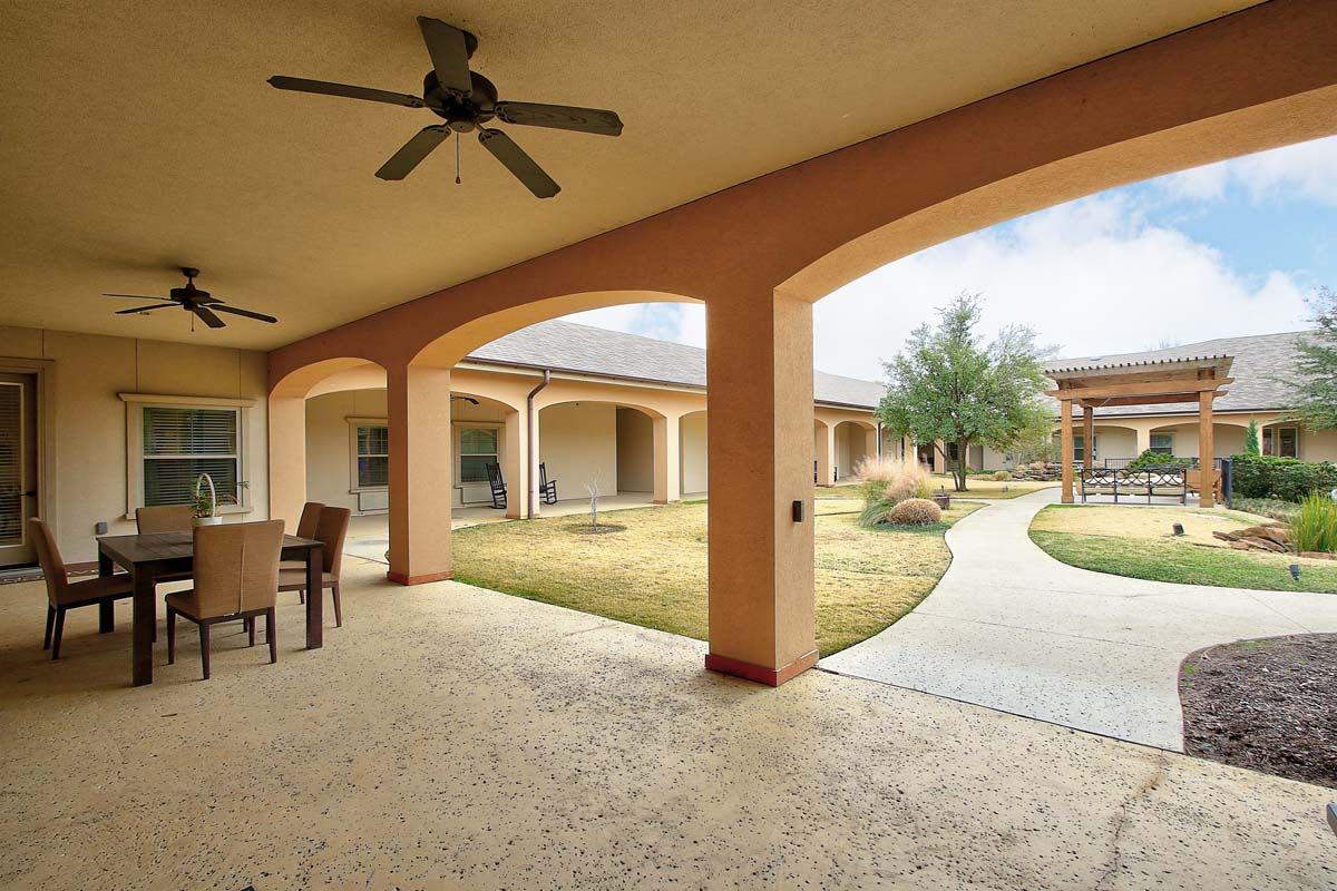 Spacious courtyard with a covered patio, arches, and outdoor furniture.